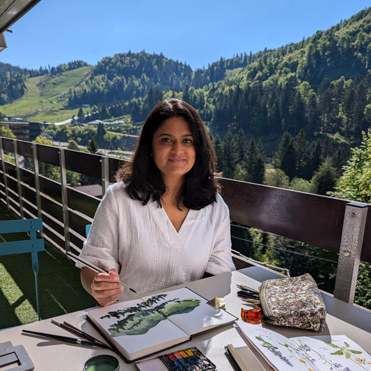 Sushma Hegde painting outdoors with a scenic mountain view